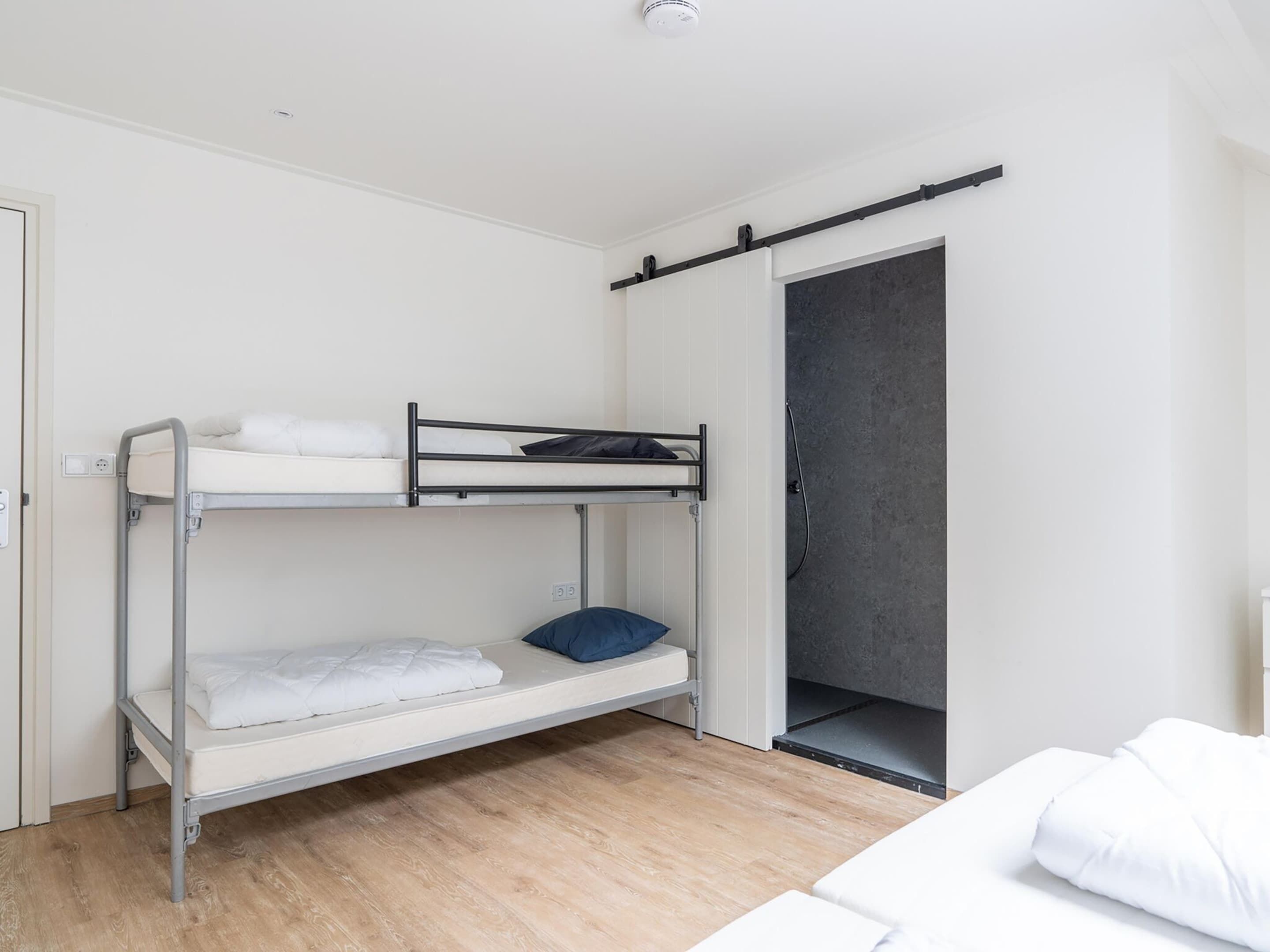 Habitación con literas y puerta corredera hacia la zona de ducha.