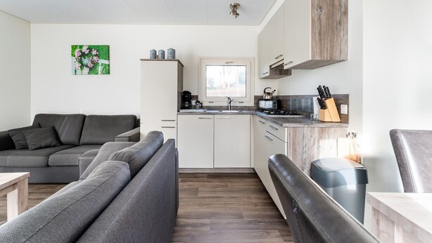 A modern kitchen with a stove, sink, and cabinets, a gray sofa, and a wooden floor. - Luxury Holiday Home in Bantega With Harbour and Sloop (Bantega)