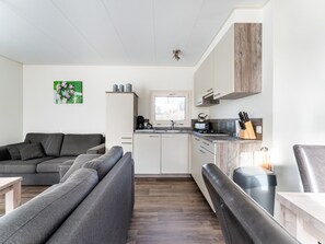 A modern kitchen with a stove, sink, and cabinets, a gray sofa, and a wooden floor. - Luxury Holiday Home in Bantega With Harbour and Sloop (Bantega)