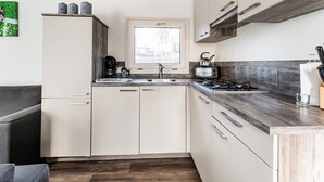 A compact kitchen with a window, a stove, a coffee maker, and a toaster. - Luxury Holiday Home in Bantega With Harbour and Sloop (Bantega)