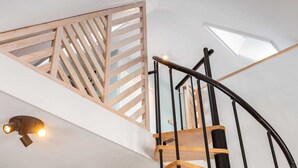 A modern staircase with wooden steps and black metal railings, leading to a lofted area with a slatted wooden partition and skylights. - Apartment Near Sneekermeer Water Sports (Offingawier)