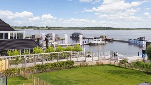 A lakeside property with a dock, boats, and a grassy area. - Apartment Near Sneekermeer Water Sports (Offingawier)