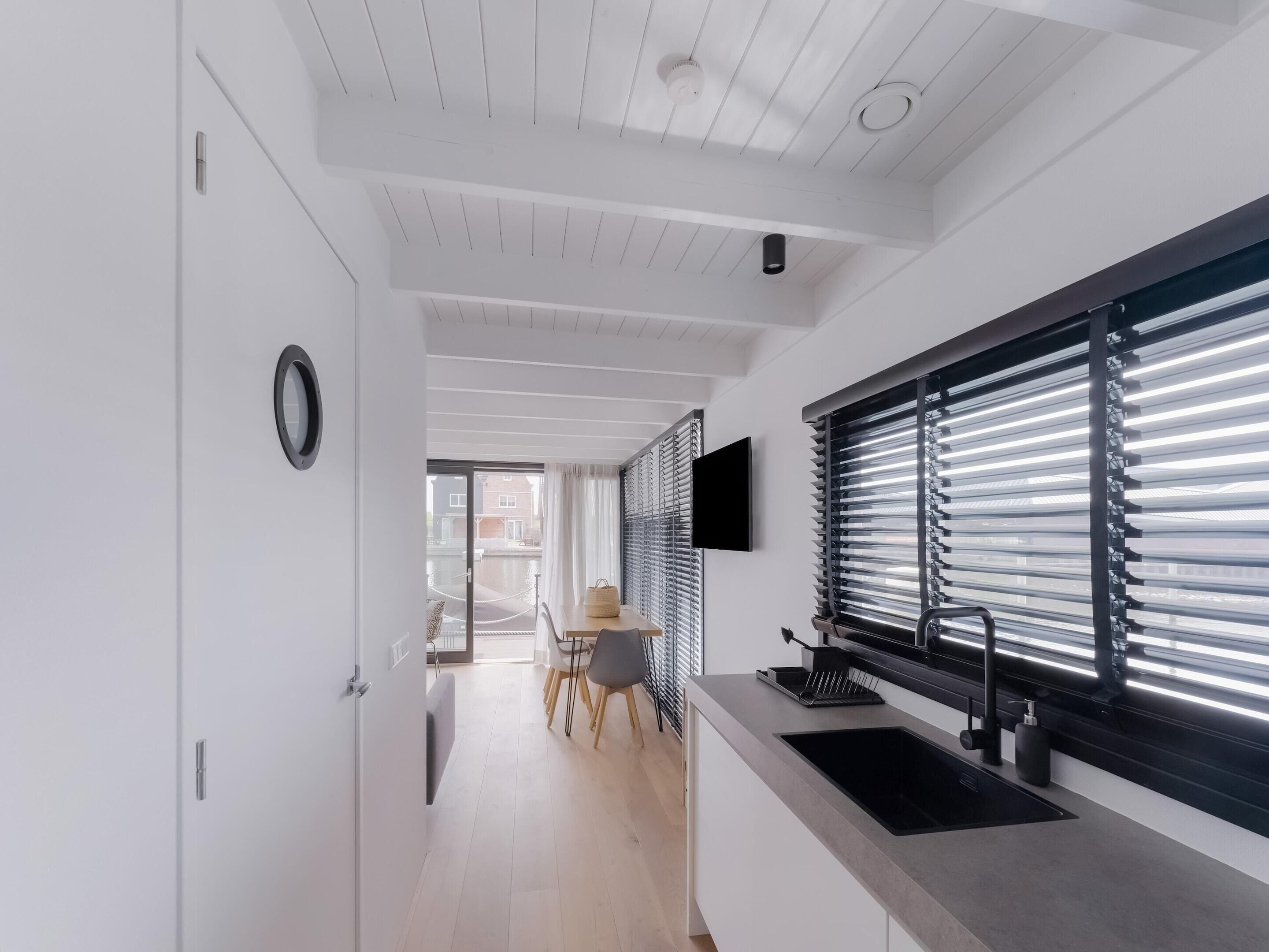 Eine moderne Küche mit integriertem Spülbecken, einem Flachbildfernseher und einem Fenster mit Jalousien.