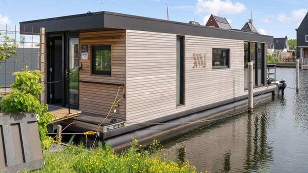 A floating houseboat with a wooden exterior, a small deck, and a window. - Houseboat in Stavoren With Waterfront Views (Stavoren)