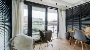 A modern room with a large sliding glass door leading to a balcony, wicker chairs, a small table, and a glass jar on the floor. - Houseboat in Stavoren With Waterfront Views (Stavoren)