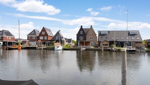 A canal with houses on one side and boats docked along the water. - Houseboat in Stavoren With Waterfront Views (Stavoren)