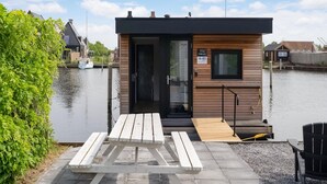 A small wooden cabin with a door, a window, and a sign indicating it is a TMBoots. - Houseboat in Stavoren With Waterfront Views (Stavoren)