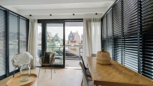 A modern dining area with a wooden table, white chairs, and a view of a canal and houses through large windows. - Houseboat in Stavoren With Waterfront Views (Stavoren)