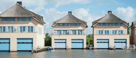 Drie strandhuizen met rieten daken en blauwe luiken, elk met een garage.