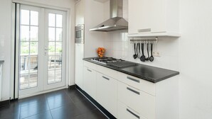Una cocina moderna con estufa a gas, armarios blancos y encimera negra.