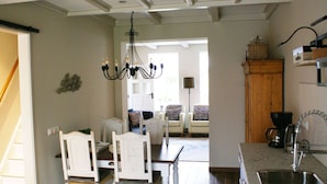 A kitchen with a sink, a chandelier, and a dining area with chairs and a table. - Holiday Home Paesens Near Wadden Sea (Paesens)