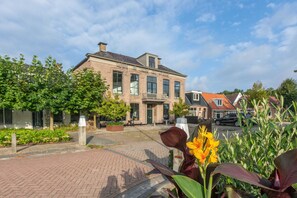 A traditional brick building with a large entrance, a balcony, and a paved courtyard with plants. - Inn in Ternaard Near Heritage (Ternaard)