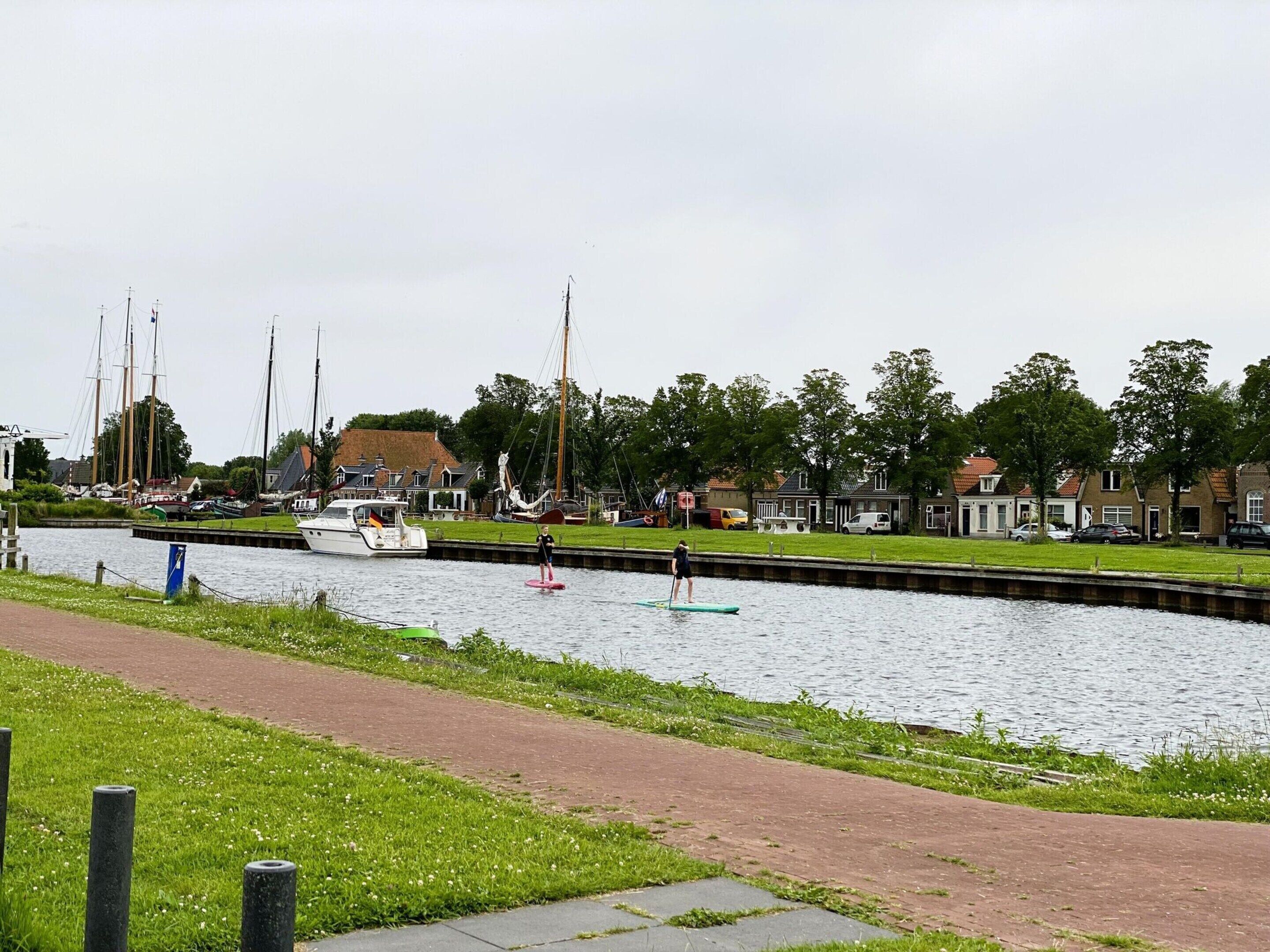 A canal with boats, a pedestrian path, and houses along the water.