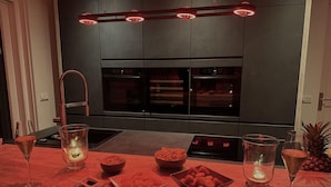 A modern kitchen with dark cabinetry, stainless steel appliances, and a red-lit countertop. - Holiday Home in Stavoren by Private Jetty (Stavoren)