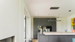 A modern kitchen with dark cabinetry, a large island, and a view through the window. - Holiday Home in Stavoren by Private Jetty (Stavoren)