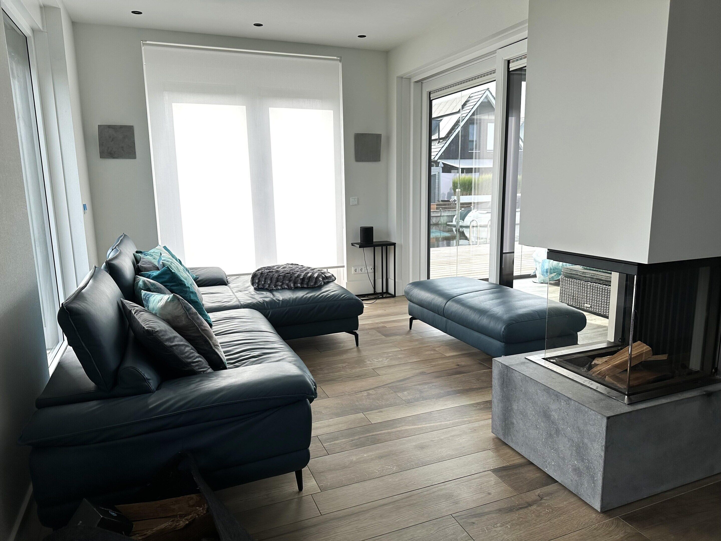Un salon moderne avec un canapé en cuir, un fauteuil bleu et une cheminée.