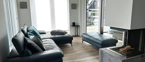 Un salon moderne avec un canapé en cuir, un fauteuil bleu et une cheminée.