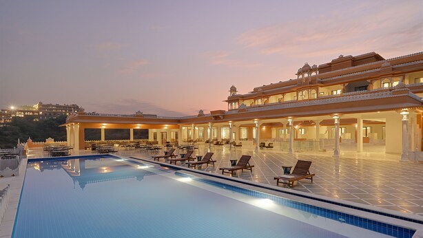 A large indoor swimming pool with lounge chairs and a covered seating area. - Fateh Vilas by Fateh Collection (Udaipur)