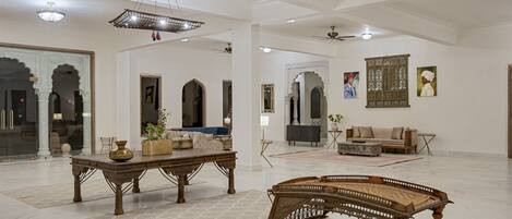 A spacious living area with a traditional wooden coffee table, a sofa, and a dining table with chairs.