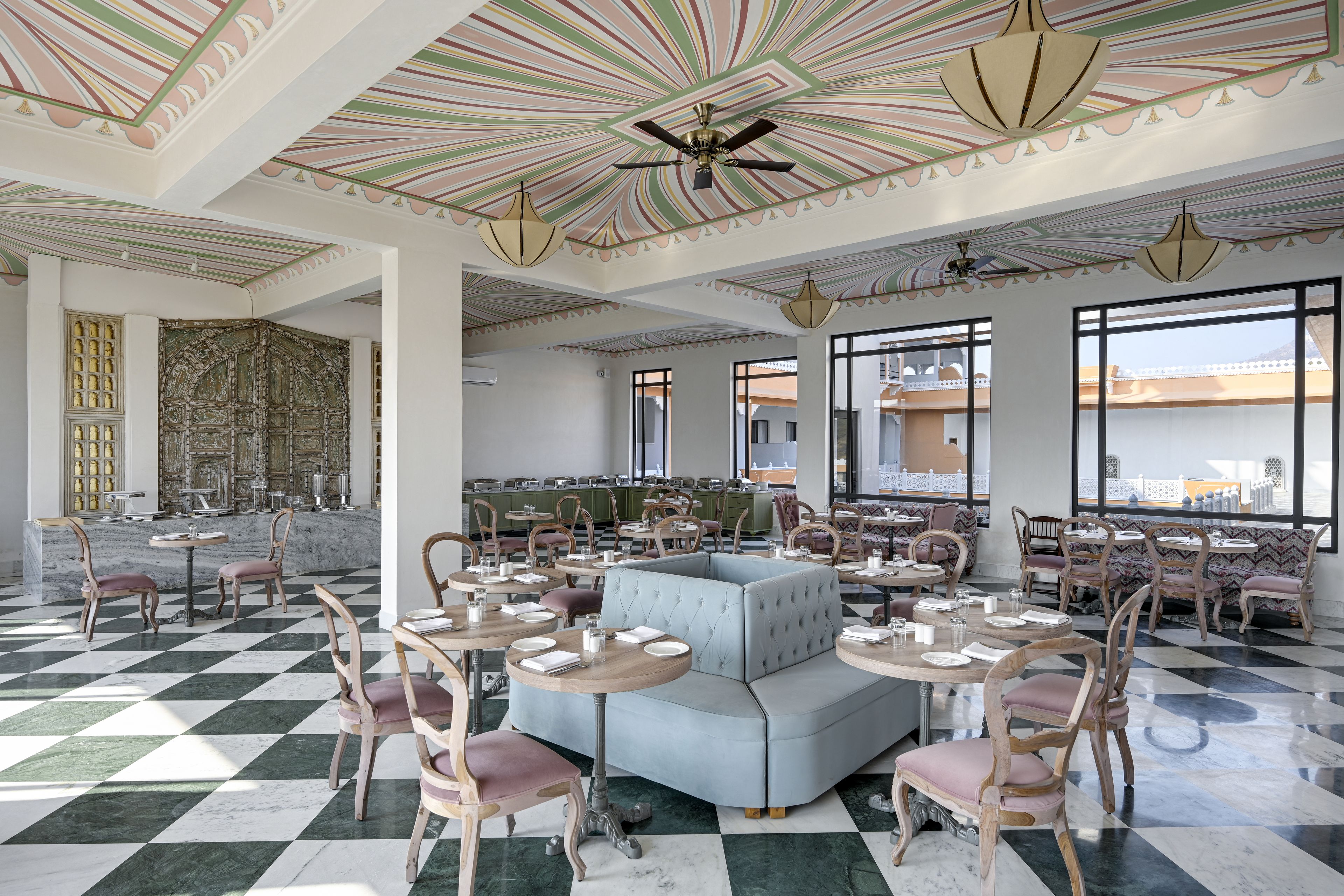 A spacious dining area with checkered flooring, multiple seating arrangements, and a decorative ceiling.