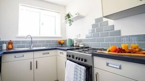 Eine moderne Küche mit Gasherd, weißen Schränken, einer blauen Arbeitsplatte und einem Fenster über der Spüle.