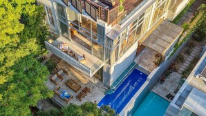 Ein modernes Mehrstöckige Gebäude mit Dachterrasse, Pool und üppiger Bepflanzung rund um das Anwesen.