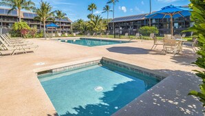 Zona de piscina con sillas de descanso, una piscina y un edificio con paneles solares.