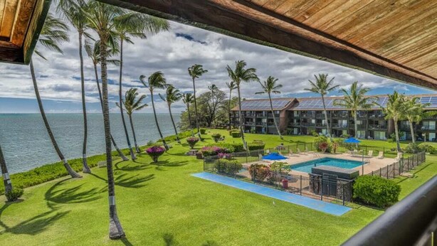 Un resort con piscina, palmeras y vista al océano.