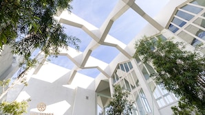 Ein modernes Gebäude mit geometrischer Architektur, großen Fenstern und umgebender Bepflanzung.