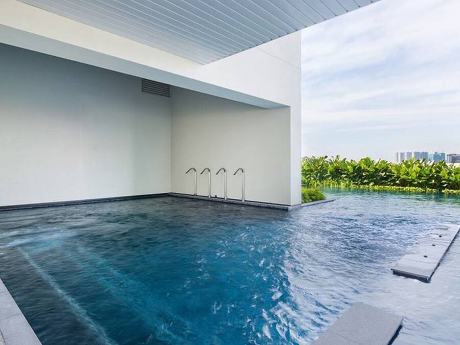 Piscina interior moderna com água cristalina, design minimalista e vista para áreas verdes e edifícios ao fundo.