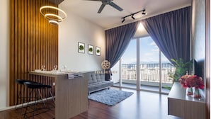 Ein modernes Wohnzimmer mit einer Couch, einem Essbereich mit Tisch und Stühlen, einem Deckenventilator und einem großen Fenster mit Vorhängen.
