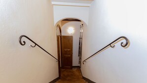 A staircase with a wooden door at the top, leading to a room with a white wall and a round light fixture. - [Old Town] Elegant Suite, Wi-fi & Comfort (San Gimignano)