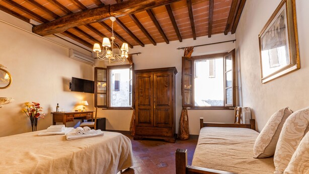 A bedroom with two beds, wooden furniture, a chandelier, and a television. - [Old Town] Elegant Suite, Wi-fi & Comfort (San Gimignano)