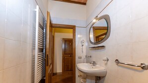 A bathroom with a white sink, a mirror, a towel rack, and a door leading to another room. - [Old Town] Elegant Suite, Wi-fi & Comfort (San Gimignano)