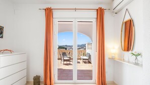 Ein Zimmer mit einer Glasschiebetür, die auf eine Terrasse im Freien mit Blick auf die Stadt und die Hügel führt.