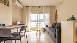 Un soggiorno moderno con divano, tavolo da pranzo con sedie, televisione e balcone con vista.