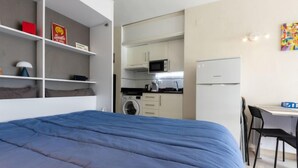 Una camera compatta con un letto grande, un angolo cottura piccolo e un'area pranzo.