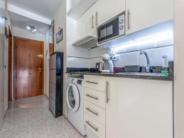 A compact kitchen with a microwave, washing machine, and a coffee maker. - Font de Mar by Interhome (Salou)