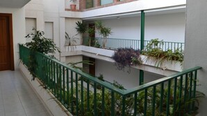 Een meerlaags woongebouw met balkons, groene reling en potplanten.