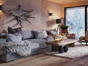 Een moderne woonkamer met een grijze bank, een houten salontafel en een groot decoratief object aan de muur.