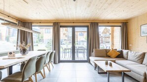 A modern living room with a wooden ceiling, a sofa set, a dining table with chairs, and large windows with curtains. - #5b mit Sauna & Pool by Interhome (Sankt Georgen am Kreischberg)