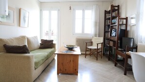 A living room with a sofa, a wooden coffee table, a chair, a bookshelf, and a radiator. - In the shadow of Acropolis - Breathtaking view  (ATHENS)