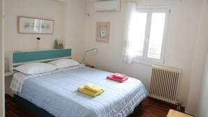 A bedroom with a bed, a window with curtains, an air conditioning unit, and a radiator. - In the shadow of Acropolis - Breathtaking view  (ATHENS)