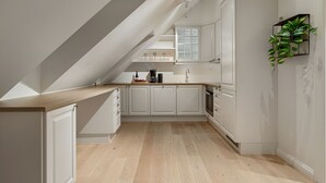A modern kitchen with white cabinetry, a wooden countertop, and a skylight. - ARCTIC HOMES - THE RETREAT (Tromsø)