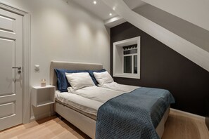 A bedroom with a bed, a nightstand, a window, and a door. - ARCTIC HOMES - THE RETREAT (Tromsø)