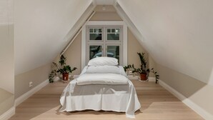 A bedroom with a sloped ceiling, a bed, and two potted plants. - ARCTIC HOMES - THE RETREAT (Tromsø)