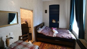 Quarto com cama, cómoda, espelho, janela com cortinas e luminária suspensa.
