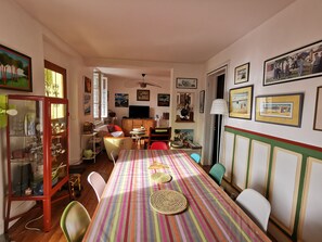 A dining area with a long table covered by a striped tablecloth, surrounded by chairs.