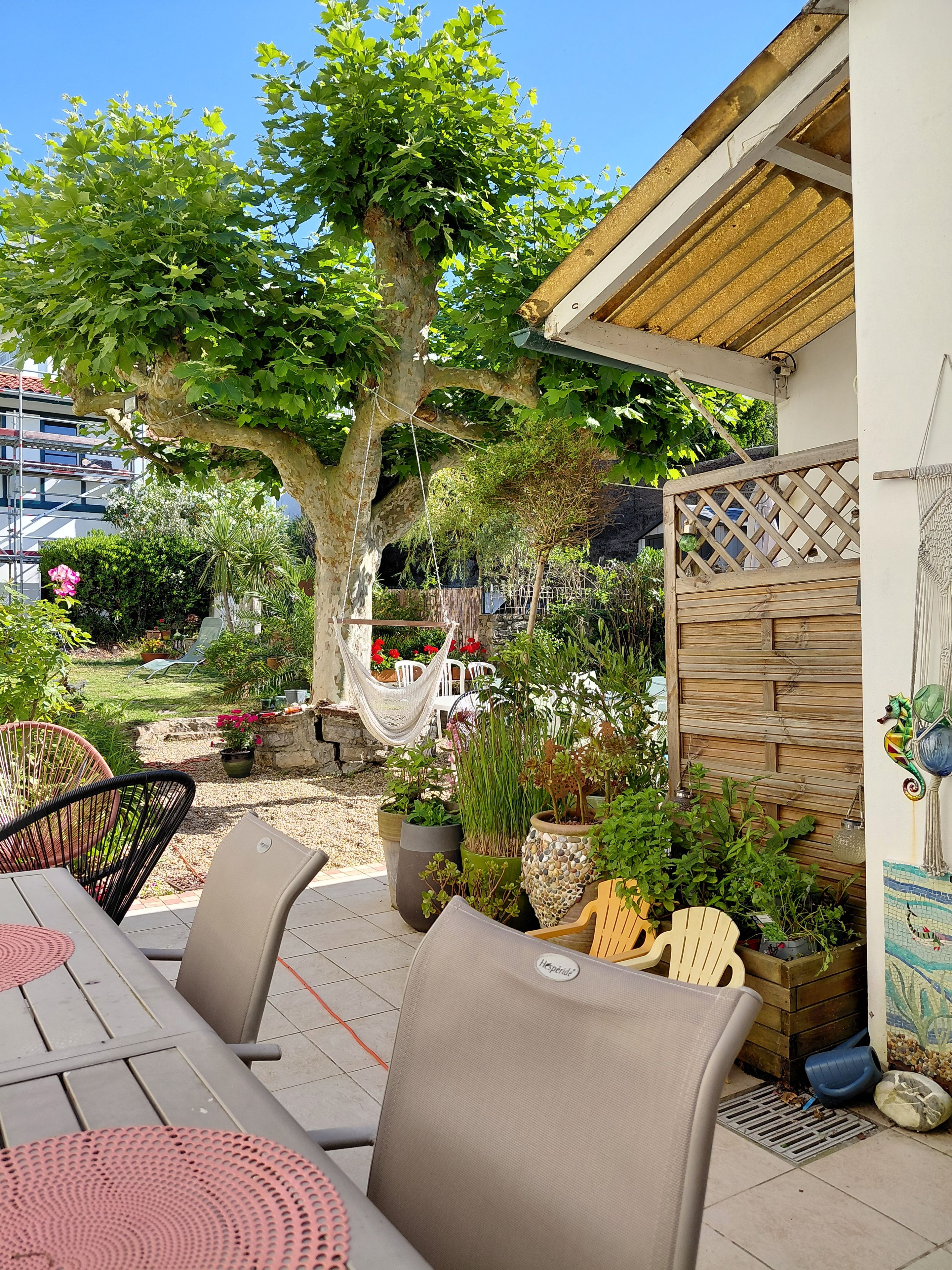 Eine Außenpatio mit Esstisch, Stühlen und einer Hängematte.