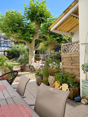 Un patio al aire libre con una mesa de comedor, sillas y una hamaca.